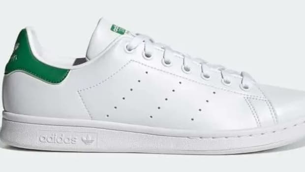 Side view of a white and green adidas shoe.