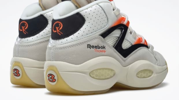 Back view of white, black, and orange Reebok shoes.