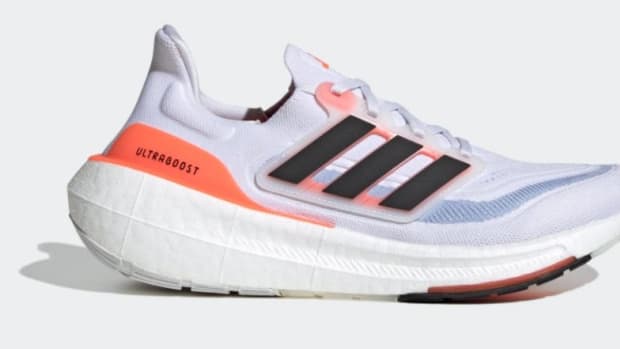 Side view of a white and orange adidas shoe.