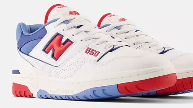 Side view of white, red, and blue New Balance shoes.