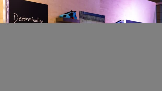 Donovan Mitchell's blue adidas sneakers line the wall at an event.