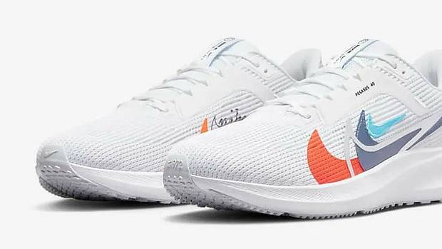 Side view of white and orange Nike running shoes.