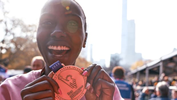 Sharon Lokedi holds up her medal after the 2023 New York City Marathon.