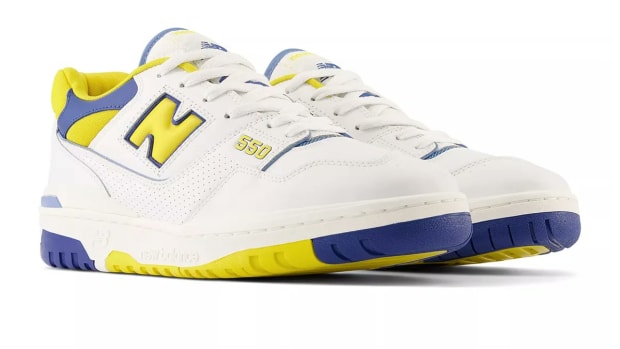 Side view of white, yellow, and blue New Balance sneakers.