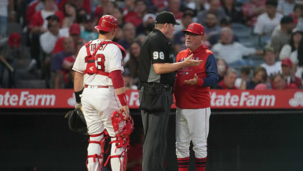 Jun 6, 2022; Anaheim, California, USA; Los Angeles Angels manager Joe Maddon (right) talks with umpire Chris Conroy (98) as catcher Max Stassi (33) watches in the fifth inning against the Boston Red Sox at Angel Stadium. Mandatory Credit: Kirby Lee-USA TODAY Sports