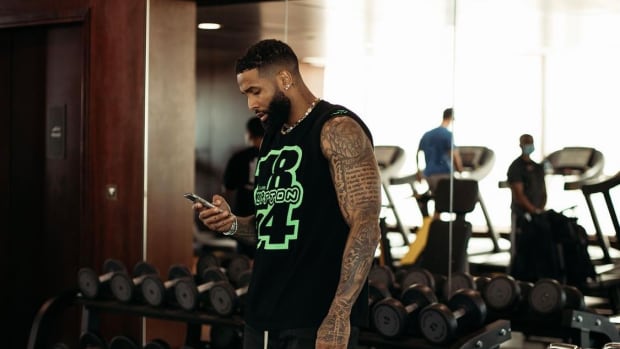 Odell Beckham Jr. looking at his phone in weight room while wearing bright green shoes.