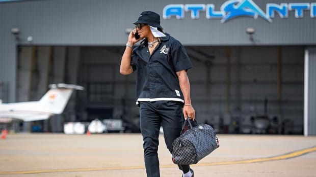 Chase Claypool walks down the tarmac in all black outfit and bag.