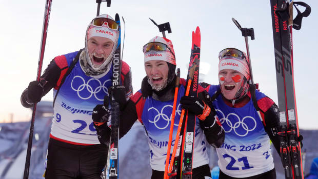 Christian Gow, center, and Scott Gow, right, celebrate after the men's 15-kilometer biathlon.