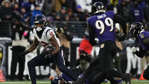Texans wide receiver Nico Collins runs the ball against Baltimore Ravens safety Geno Stone and linebacker Odafe Oweh during the first quarter of a 2024 AFC divisional round game at M&T Bank Stadium.
