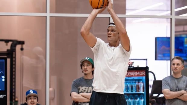 Tom Brady shoots a basketball in a New York City gym.