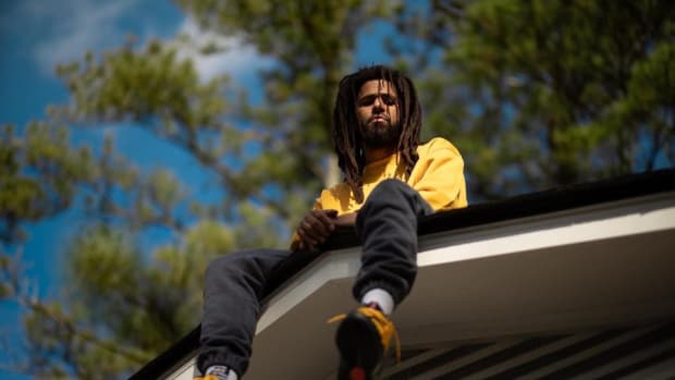 J. Cole sitting on a roof.