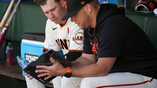 SF Giants starting pitcher Anthony DeSclafani (left) watches a tablet with pitching coach Andrew Bailey (right) during the fifth inning against the Pittsburgh Pirates at Oracle Park. (2023)