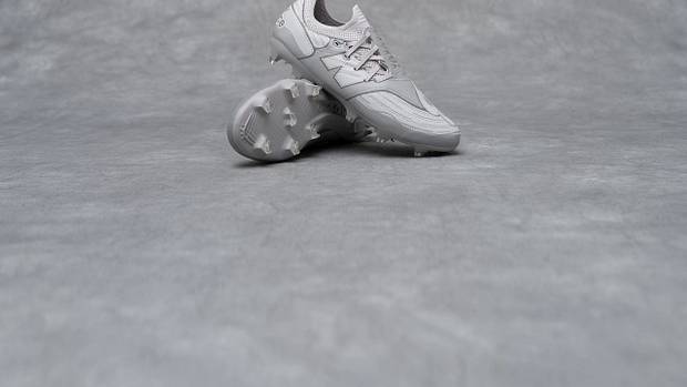 Side view of grey New Balance soccer cleats.