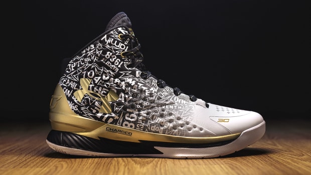 Side view of Stephen Curry's white, black, and gold Under Armour shoe.
