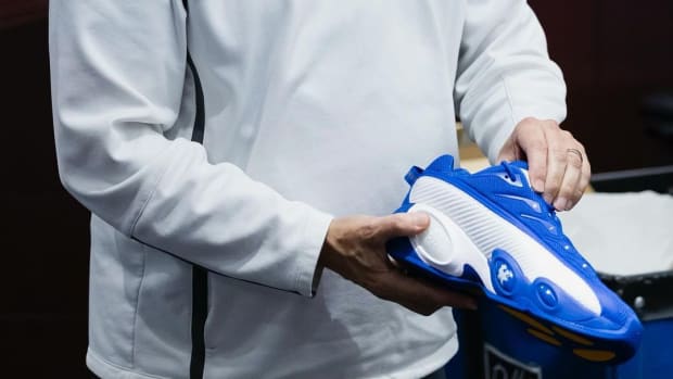 Kentucky Wildcats basketball coach John Calipari holds Drake's blue and white Nike sneakers.