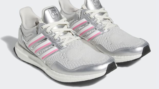 View of silver, white, and pink adidas shoes.