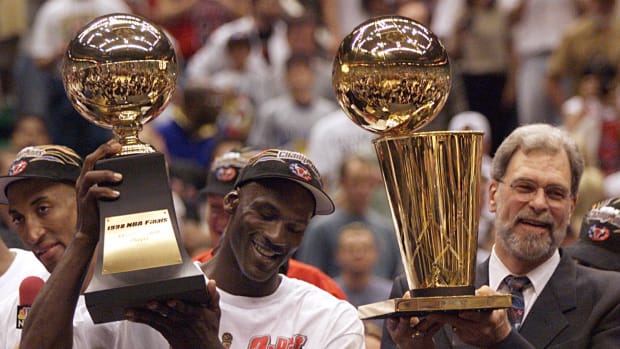 Michael Jordan holds the MVP trophy and coach Phil Jackson holds the championship trophy after the Bulls beat the Jazz to win their sixth title in 1998.