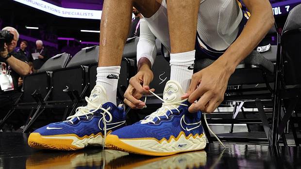 Victor Wembanyama tying his blue and white Nike shoes.