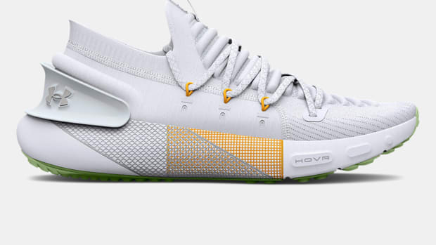 Side view of white and yellow Under Armour running shoe.