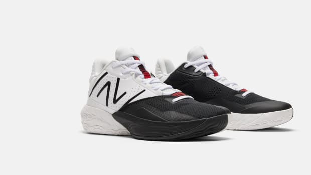 Side view of white, black, and red New Balance basketball shoes.
