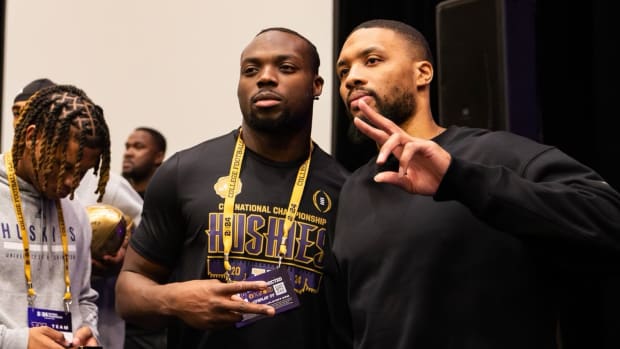 Damian Lillard poses for pictures with the Washington Huskies football team.