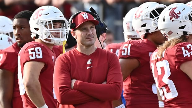 Washington State head coach Jake Dickert standing on the sidelines with his team.