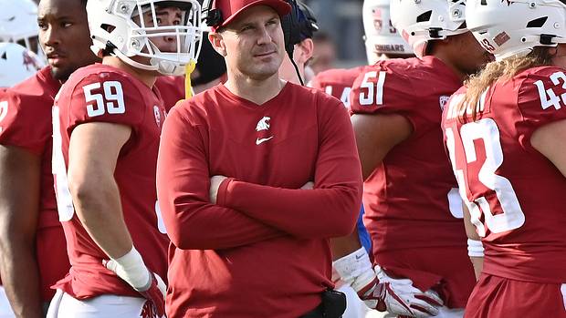 Washington State head coach Jake Dickert standing on the sidelines with his team.