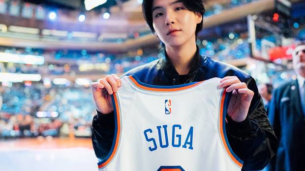 Suga holds up a Knicks jersey before a game.