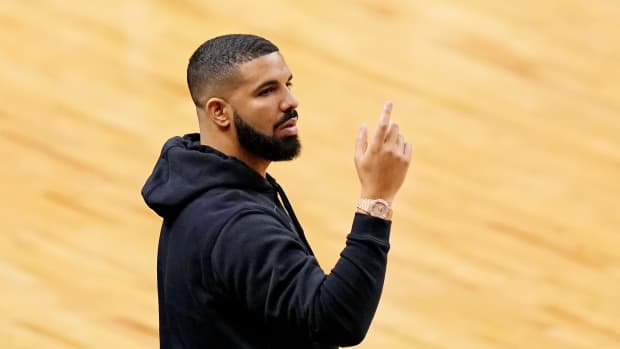 Drake standing courtside during a basketball game.
