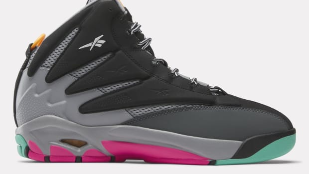 Side view of a black, grey, and pink Reebok shoe.