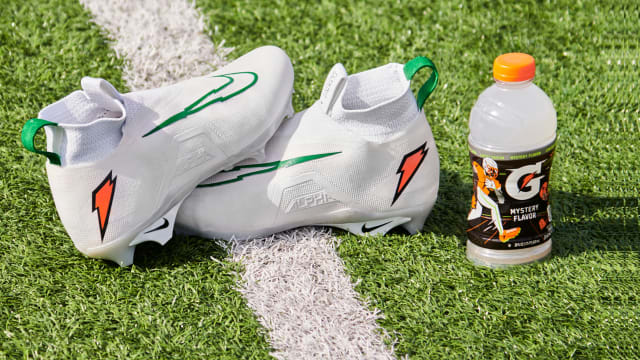 Shedeur Sanders' white and green Nike cleats next to a Gatorade bottle.