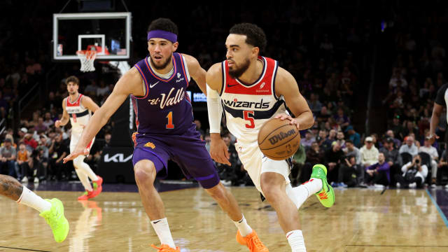 Washington Wizards guard Tyus Jones (5) drives to the net against Phoenix Suns guard Devin Booker (1) during the first quarter at Footprint Center. 