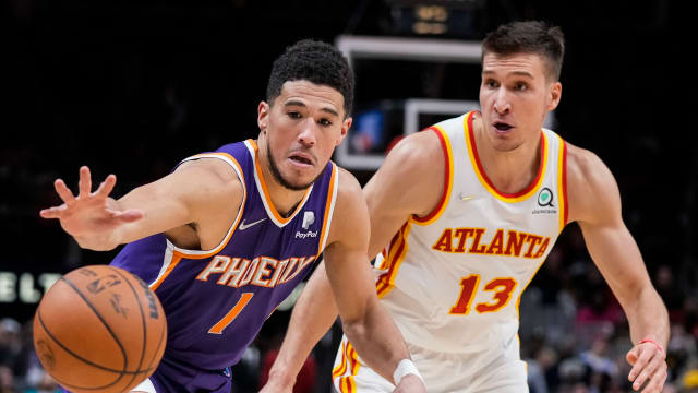 Suns guard Devin Booker and Hawks guard Bogdan Bogdanovic reach for the ball.