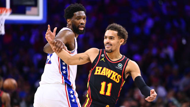 Hawks guard Trae Young reacts as 76ers center Joel Embiid grabs him.
