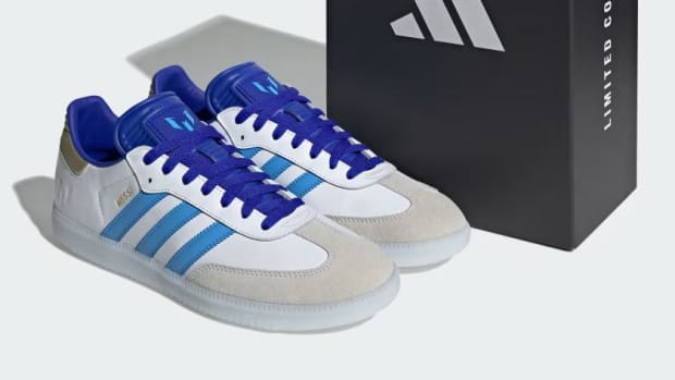 Side view of Lionel Messi's white and blue adidas Sambas.
