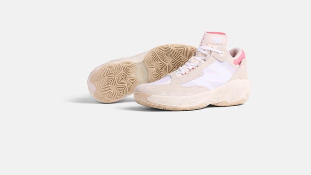 Side view of tan and pink New Balance basketball shoes.