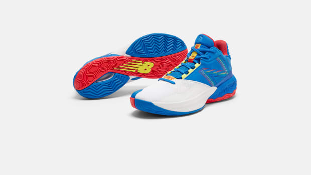 Side view of white, blue, and red New Balance basketball shoes.