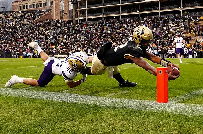 Colorado Buffaloes quarterback Brendon Lewis (12) scores a touchdown ahead of Washington Huskies linebacker Carson Bruener (42) in the fourth quarter at Folsom Field.
