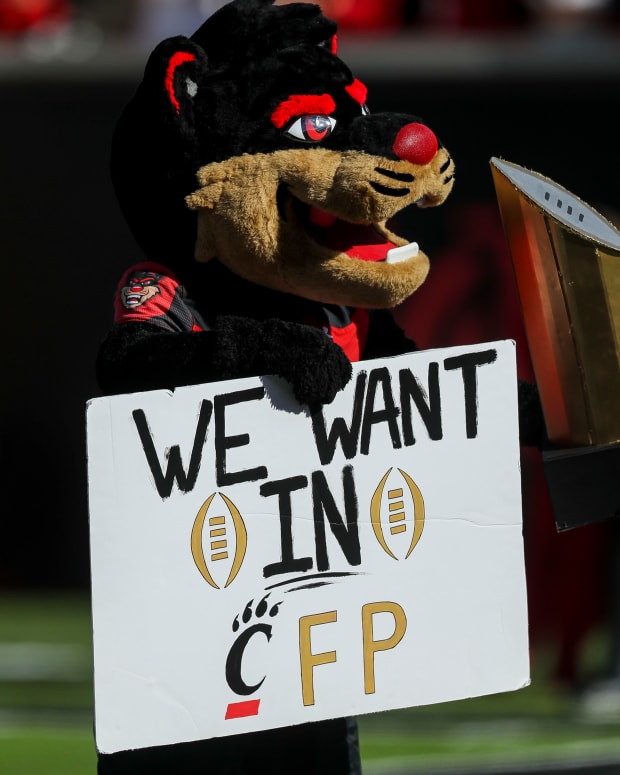 Oct 16, 2021; Cincinnati, Ohio, USA; The Cincinnati Bearcats mascot poses with a sign and a replica of the College Football Playoff National Championship trophy at the end of the game against the UCF Knights at Nippert Stadium. Mandatory Credit: Katie Stratman-USA TODAY Sports