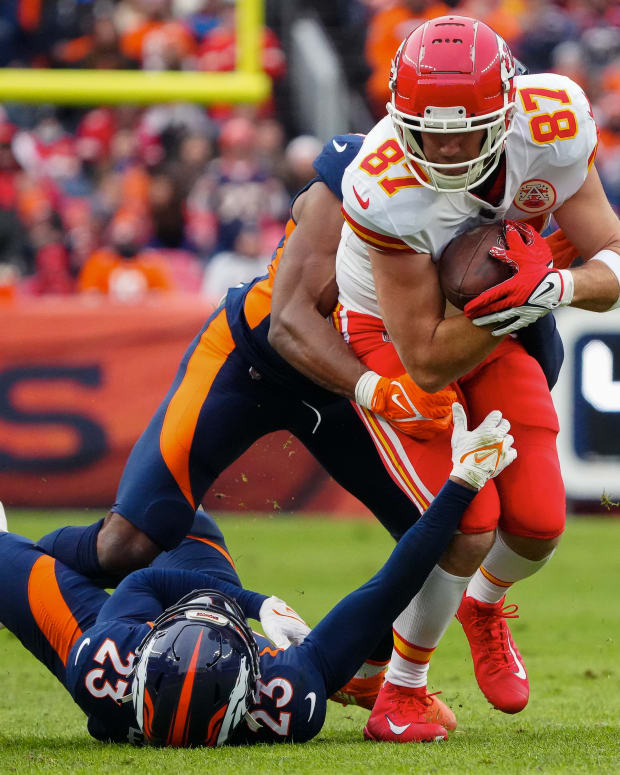 Jan 8, 2022; Denver, Colorado, USA; Kansas City Chiefs tight end Travis Kelce (87) is tackled by Denver Broncos cornerback Kyle Fuller (23) and linebacker Jonas Griffith (50) in the first quarter at Empower Field at Mile High. Mandatory Credit: Ron Chenoy-USA TODAY Sports