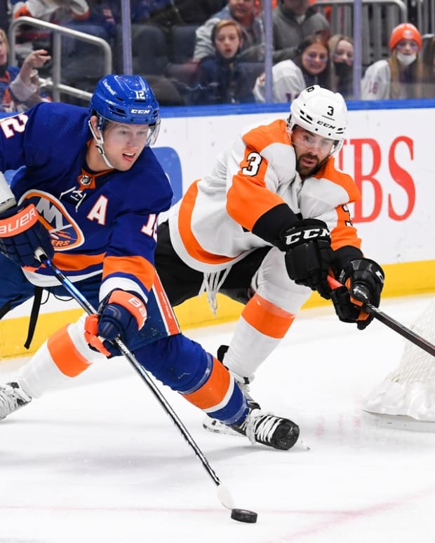Jan 17, 2022; Elmont, New York, USA; New York Islanders right wing Josh Bailey (12) looks to pass from behind the net defended by Philadelphia Flyers defenseman Keith Yandle (3) during the second period at UBS Arena. Mandatory Credit: Dennis Schneidler-USA TODAY Sports