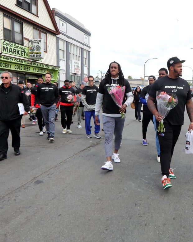 Members of the Buffalo Bills walk to the site of the last Saturday's mass shooting at the Tops supermarket in Buffalo. After visiting the site, the team helped distribute food to members of the community.