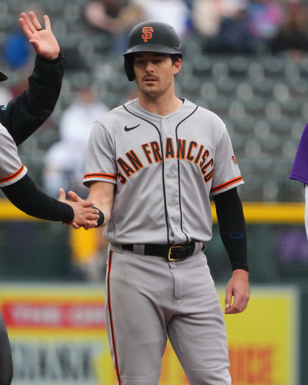 SF Giants outfielder Mike Yastrzemski high-fives third-base coach Mark Hallberg during their game against the Rockies on September 22, 2022.