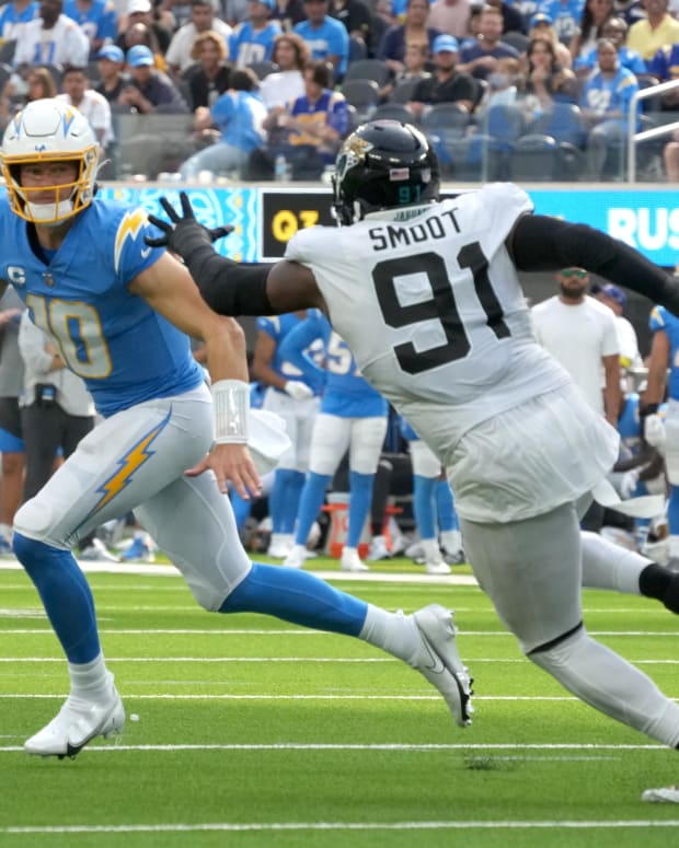Sep 25, 2022; Inglewood, California, USA; Los Angeles Chargers quarterback Justin Herbert (10) runs the ball under pressure from Jacksonville Jaguars defensive end Dawuane Smoot (91) in the third quarter at SoFi Stadium. Mandatory Credit: Kirby Lee-USA TODAY Sports