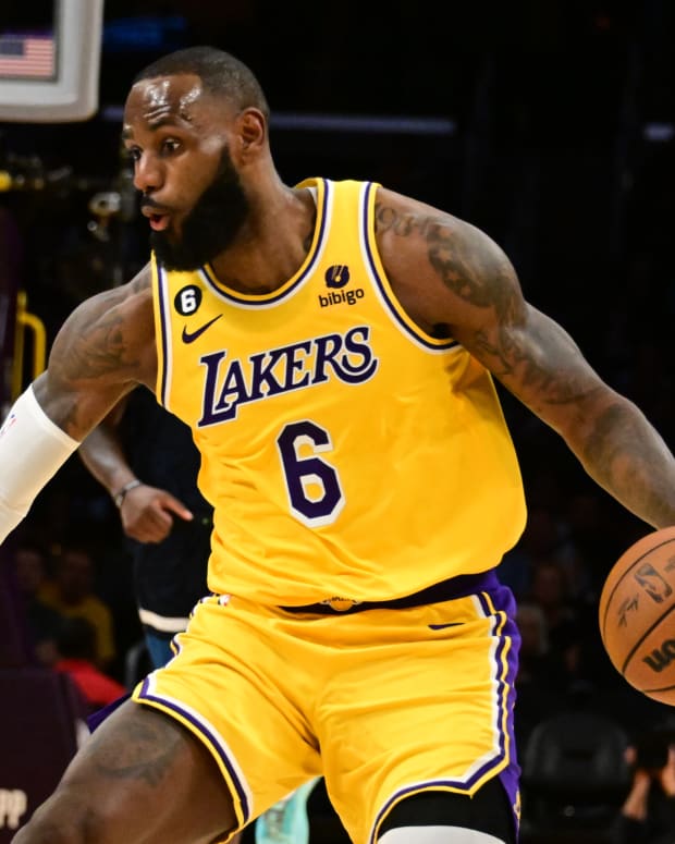 LeBron James goes to dribble a basketball in a yellow Lakers uniform