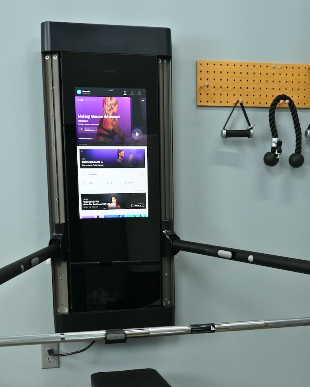 A Tonal home workout system, with touchscreen, adjustable arms and attachments.