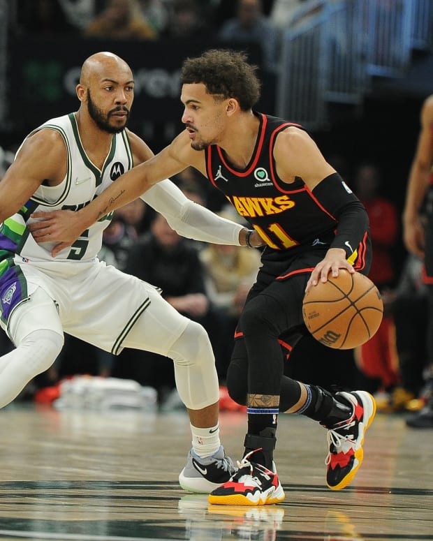 Trae Young dribbles the ball against Bucks guard Jevon Carter.