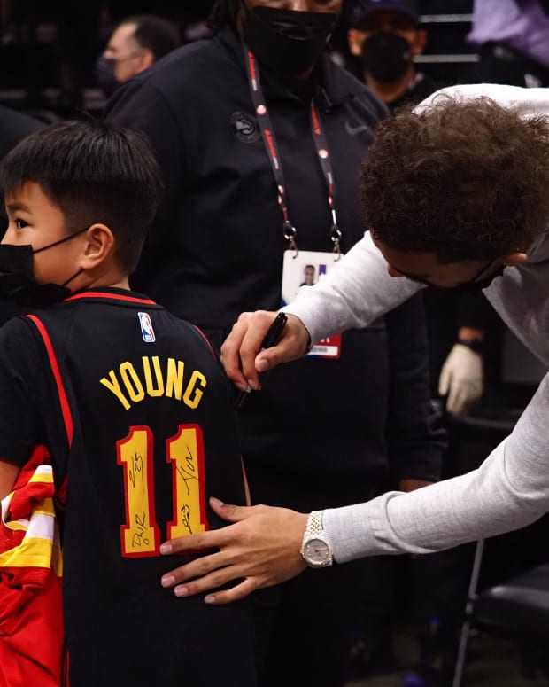 Jan 5, 2022; Sacramento, California, USA; Atlanta Hawks guard Trae Young (11) signs the jersey of a young fan after the game against the Sacramento Kings at Golden 1 Center.