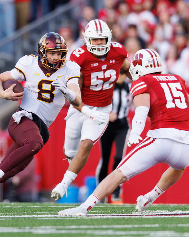 Minnesota quarterback Athan Kaliakmanis running with the football with John Torchio preparing to tackle him in the open field.