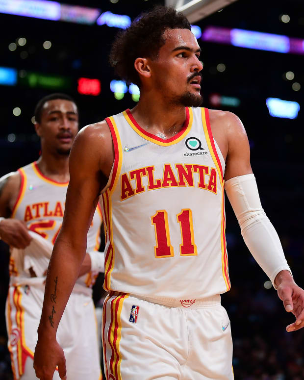 Trae Young and John Collins walk towards the bench.